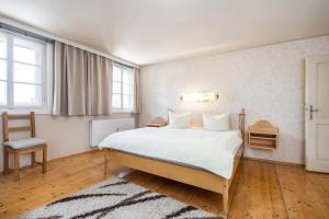 ein Schlafzimmer mit einem großen weißen Bett und einem Stuhl in der Unterkunft Landhaus Lindner Appartements in Fügen
