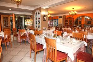 un restaurante con mesas y sillas con manteles blancos en Hotel Los Arcos en El Alquián