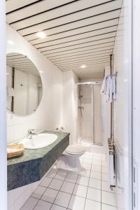 ein Badezimmer mit einem Waschbecken, einem WC und einem Spiegel in der Unterkunft Malecot Hotel by F-Hotels in Blankenberge