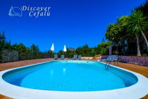 een groot zwembad met blauw water in een tuin bij Residence Villa Santa Lucia in Cefalù