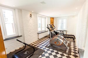 Ein Raum mit einem Fitnessraum und Trainingsgeräten auf einem Schachbrettboden in der Unterkunft Malecot Hotel by F-Hotels in Blankenberge