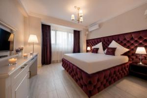 a bedroom with a large bed with a red velvet headboard at Hotel Casa Fiori in Bucharest