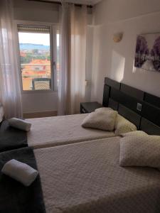 um quarto com 2 camas e uma janela em Hotel Costa Mar em Loredo