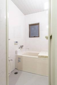 La salle de bains blanche est pourvue d'une baignoire et d'une fenêtre. dans l'établissement Ikebukuro Yamase Building #GR1, à Tokyo