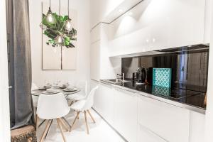 マドリードにあるBelén Modern y luxury space near Plaza Mayorの白いキャビネット、テーブルと椅子付きのキッチンが備わります。