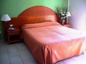 - une chambre avec un grand lit orange et une table de chevet dans l'établissement Hotel Florida Tirrenia, à Tirrenia