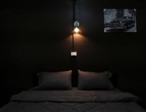 a dark room with a bed with a light on the wall at Pangtip in Lampang