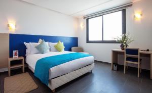 Un dormitorio con una cama azul y blanca y una ventana en Relax Hotel Casa Voyageurs, en Casablanca