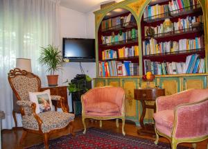uma sala de estar com cadeiras e uma estante de livros com livros em B&B Il Glicine Fiorito em Lido di Venezia