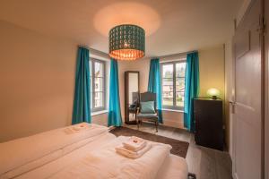 1 dormitorio con 2 camas, cortinas azules y lámpara de araña en Dependance Penthouse en Interlaken