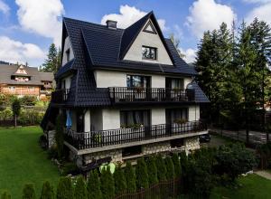 una casa con un tetto nero su un cortile verde di Willa Pod Lasem a Kościelisko