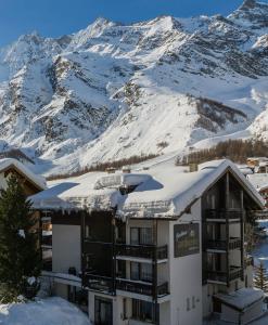 a hotel with snow covered mountains in the background at Ambiente Guesthouse in Saas-Fee