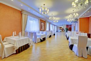 un salón de banquetes con mesas blancas y lámparas de araña en SQ Hotel, en Volgograd