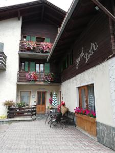 - un bâtiment avec une terrasse dotée d'une table et de chaises dans l'établissement Garni Delia, à Livigno