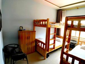 a room with three bunk beds and a desk at The Silk Road Travelers Hostel in Zhangye