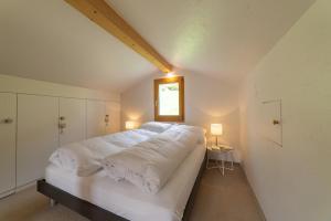 uma grande cama branca num quarto com uma janela em Steinrüti em Wildhaus