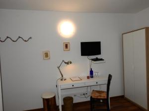 Zimmer mit einem Schreibtisch und einem TV an der Wand in der Unterkunft La Chacra Pension in Erftstadt