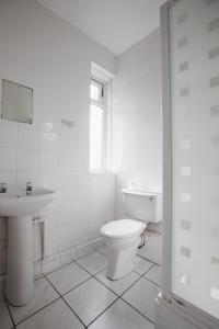 a white bathroom with a toilet and a sink at Dunes Hotel in Whitley Bay