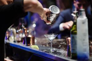 un barista che prepara un drink in un bicchiere di Martini di Il Decameron Luxury Design Hotel a Odessa