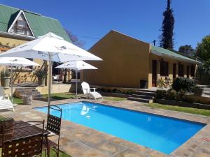 a swimming pool with an umbrella and a house at 17 on Bird Guest House in Beaufort West