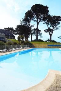 a large blue swimming pool with lounge chairs and trees at Résidence Néméa Iroise Armorique in Loc-Maria-Plouzané