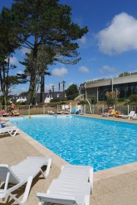 - une piscine avec 2 chaises longues dans un complexe dans l'établissement Résidence Néméa Iroise Armorique, à Loc-Maria-Plouzané