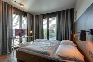 a bedroom with a large bed and a television at MEININGER Hotel Berlin Tiergarten in Berlin