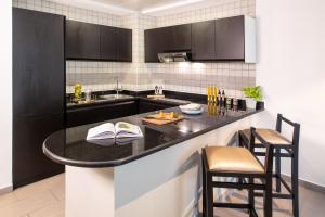 a kitchen with a black counter and some chairs at Citadines Metro Central Hotel Apartments in Dubai