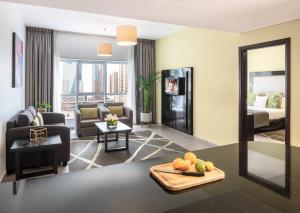 Citadines Metro Central Hotel Apartments في دبي: غرفة معيشة مع أريكة وسرير