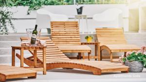 a group of wooden benches with a bottle of wine on a table at Salis Apartments in Vrsi