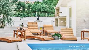 a group of chairs and a table next to a pool at Salis Apartments in Vrsi