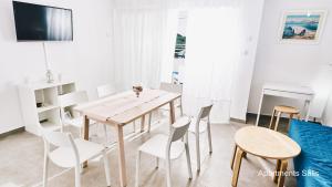 a dining room with white chairs and a wooden table at Salis Apartments in Vrsi
