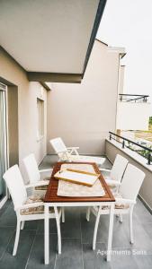 a table and white chairs on a balcony at Salis Apartments in Vrsi