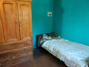 1 dormitorio con 1 cama y armario de madera en Pintoresca Cabaña Céntrica a pasos del río en Mina Clavero