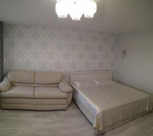a bedroom with a bed and a couch and a chandelier at Apartment IriS in Baranavichy