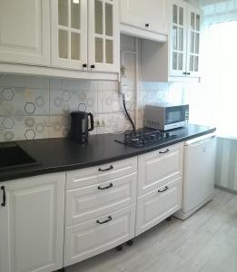a kitchen with white cabinets and a black counter top at Apartment IriS in Baranavichy
