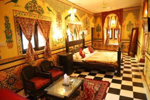 een slaapkamer met een bed en een bank en stoelen bij Singhvi's Haveli in Jodhpur