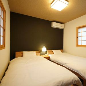 - 2 lits dans une chambre dotée d'un mur noir dans l'établissement Ryokoji Temple, à Minami Aso