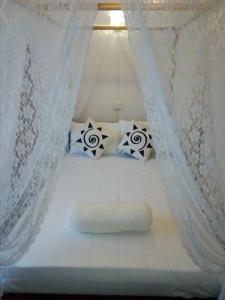 a white bed with white curtains and pillows at Zion White House in Nuwara Eliya