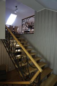 eine Holztreppe mit einem schmiedeeisernen Geländer in der Unterkunft Hotel Central Park in Velyikyy Bychkiv