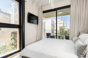 een slaapkamer met een bed en een groot raam bij Kerem Charm by Five Stay in Tel Aviv