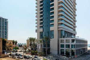 een hoog gebouw met palmbomen voor een straat bij Kerem Charm by Five Stay in Tel Aviv