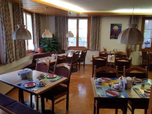 una sala da pranzo con tavoli e sedie in un ristorante di Hotel Garni Alpenruh a Lenk