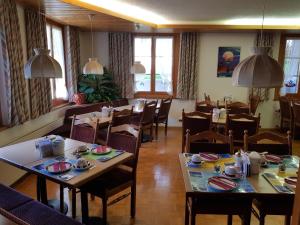 ein Esszimmer mit Tischen und Stühlen in einem Restaurant in der Unterkunft Hotel Garni Alpenruh in Lenk im Simmental