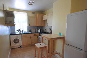 a kitchen with a refrigerator and a table in it at East End London Garden Flat in London