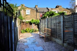 a wooden bench sitting in a garden next to a fence at East End London Garden Flat in London