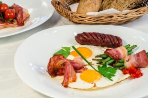 ein Frühstücksteller mit Eiern, Speck und Gemüse in der Unterkunft Eco Friendly Hotel Dália in Košice