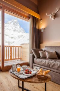 a living room with a couch and a table with food on it at Excelsior Planet in Breuil-Cervinia