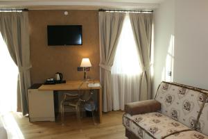 een hotelkamer met een bureau, een bank en een tafel bij Hotel Orso Grigio in Cavalese