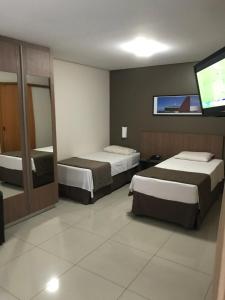 een hotelkamer met 2 bedden en een flatscreen-tv bij Crystal Place in Goiânia